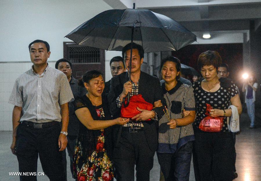 Father (front C) and mother (front 2nd R) of Wang Linjia, one of the three Chinese teenager girls who were killed in an Asiana airliner crash three weeks ago, walk into the Jiangshan Municipal Funeral Parlour with their daughter's ashes in Jiangshan, east China's Zhejiang Province, July 29, 2013. The ashes of the three Chinese teenagers were sent to the city of Jiangshan, their hometown, on Monday. The girls were aboard Asiana Airlines Flight 214 when it crashed at San Francisco International Airport on July 6. The crash killed one of the girls instantly, while another girl was run over by an ambulance. The third girl died six days later in a local hospital after sustaining critical injuries. (Xinhua/Han Chuanhao) 