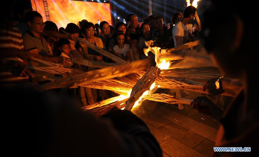 Tourists light torches to celebrate the Torch Festival at Yunnan Nationalities Village in Kunming City, southwest China's Yunnan Province, July 28, 2013. The Torch Festival, which falls around the 24th day of the sixth Chinese lunar month every year, is the traditional holiday of the Yi ethnic group and some other ethnic groups. (Xinhua/Qin Lang)