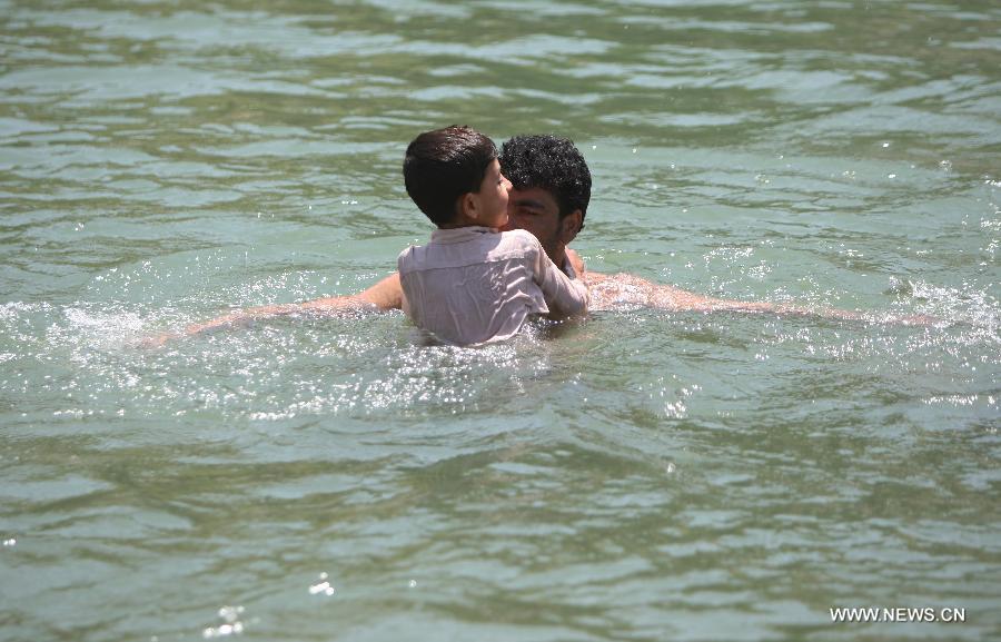 An Afghan man and his son dip in the water in a canal in Parwan province of Afghanistan on July 29, 2013. (Xinhua/Ahmad Massoud)