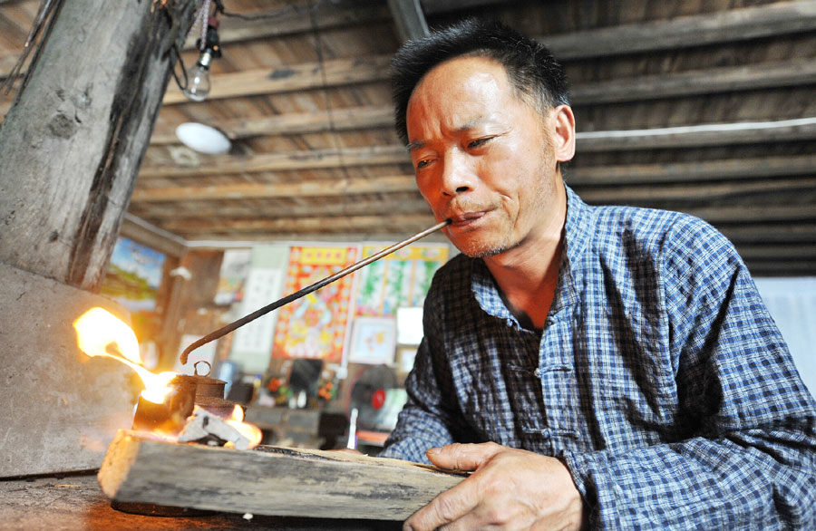 Ma Maoting uses traditional tools to create fire. (Photo/Xinhua)