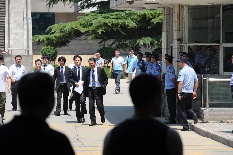 Officials from the Japanese Embassy in China (ones in black suit) walk out of the Shijiazhuang Intermediate People's Court after the trial in Shijiazhuang, north China's Hebei Province, July 30, 2013. The court on Tuesday opened a trial for a man who allegedly added poison to frozen dumplings that sickened four Chinese and nine Japanese citizens in 2008. (Xinhua/Wang Min) 