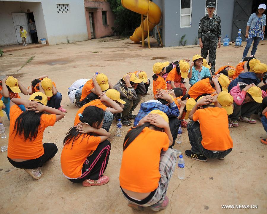 Children attend an earthquake escape drill at the provincial youth fire control and protection education base in Kunming, capital of southwest China's Yunnan Province, July 30, 2013. More than 80 migrant children in Kunming participated in a summer camp, which lasts from July 29 to Aug. 1, where they can learn knowledge related with transportation safety, fire control and earthquake protection at the base. (Xinhua/Qin Lang)