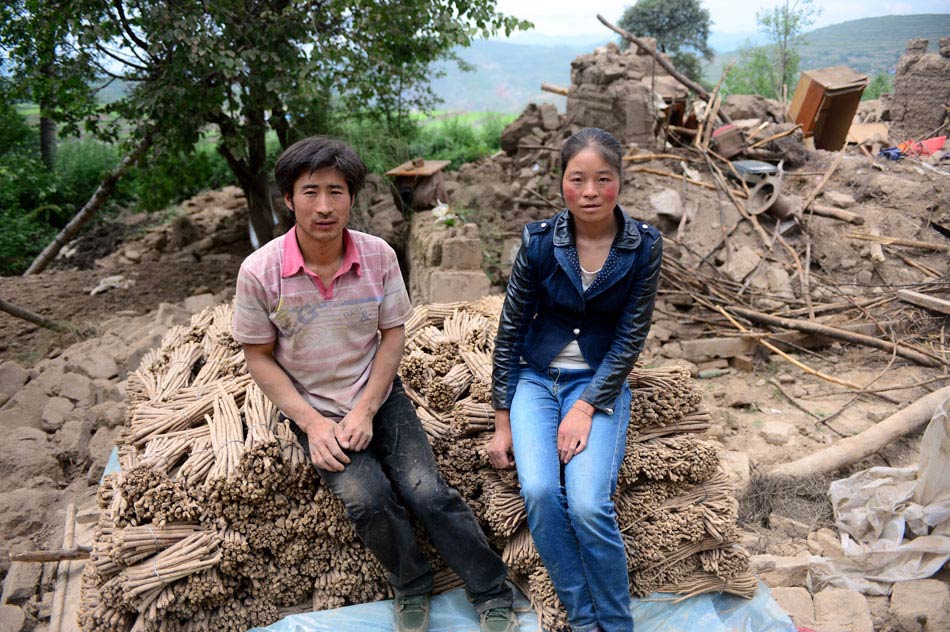 On July 24, Zhang Xianghong and his wife Ma Junxia take photo with medicinal herbs retrieved from the rubbles, which are their sole source of income. A 6.6-magnitude earthquake jolted the border of Minxian and Zhangxian counties in northwest China’s Gansu province on July 22. (Xinhua/Zhang Meng)