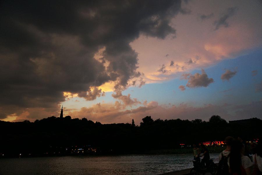 Visitors enjoy the red clouds in the sky above the West Lake in Hangzhou, capital of east China's Zhejiang Province, July 30, 2013. Hangzhou City underwent a rainmaking on Tuesday afternoon. (Xinhua/Li Zhong)
