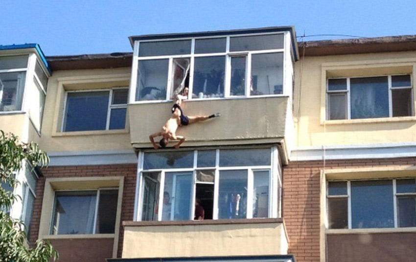 A man tries to jump from the building to commit suicide in a residential area in Changchun, captial of China's Jilin Province, July 31, 2013. While he jumped out of the window, his leg was caught by his wife. Later he was rescued by the neighbors and policemen. (Photo/Xinhua)