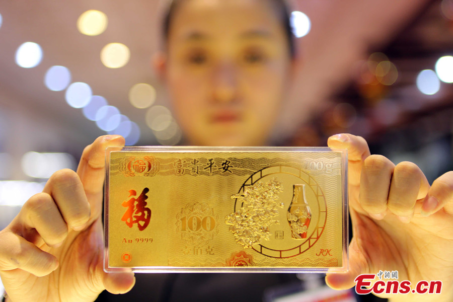 A staff member shows a piece of golden lucky money at a gold store in Taiyuan of north China's Shanxi province on Jan. 26, 2014. Lucky money is traditionally given in red packages to young people during Chinese Lunar New Year. These red envelopes are called Hung Bao, and they are usually decorated with symbols of wealth and luck. (Photo: ens.cn/Zhang Yun)