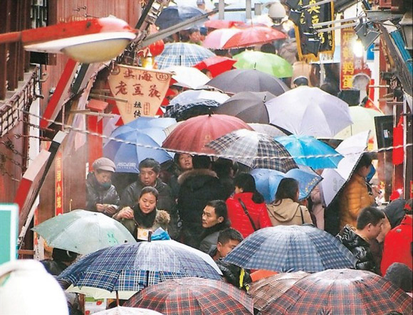 Tourists throng a street in ancient Qibao Town in Shanghai as rain falls on the last day of the weeklong Spring Festival holiday yesterday. The city tourism administration said Shanghai received more than 3.6 million tourists during the holiday, up 8.2 percent year on year, citing folk culture activities as the biggest draw. The Bund, Yuyuan Garden, the Nanjing Road Pedestrian Mall and Xujiahui received about 17 million visitors during the holiday, becoming the city’s most popular attractions. (Shanghai Daily/Dong Jun)